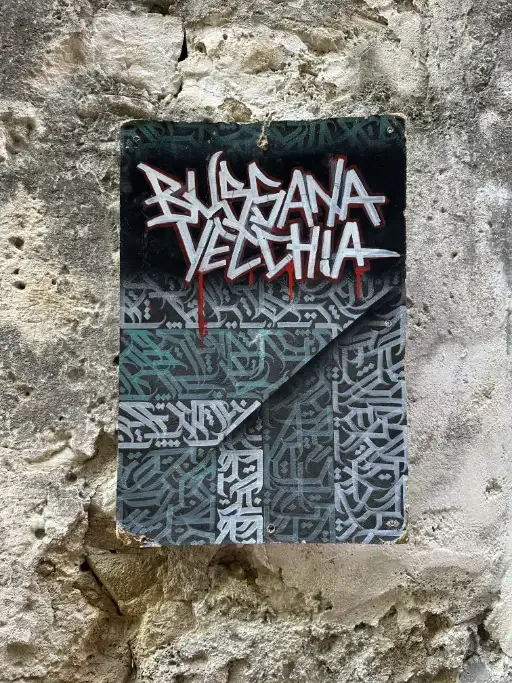 A hand painted sign in graffiti calligraphy on an old wall with the name of the village bussana vecchia