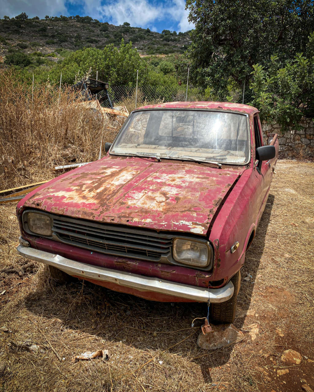 Photo showing an old abandoned car in the backyard of our house on Crete
